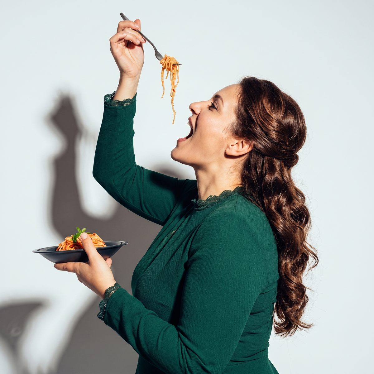 Femme en robe verte savourant une assiette de pâtes